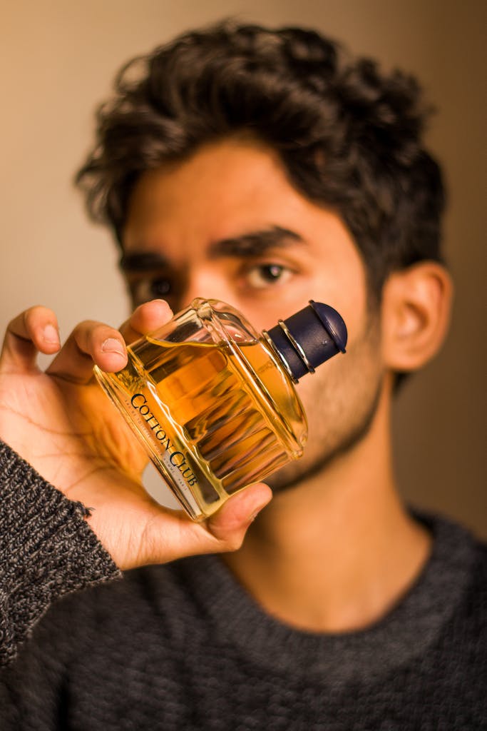 Asian man holding a perfume bottle in a close-up shot. Perfect for fashion and beauty themes.