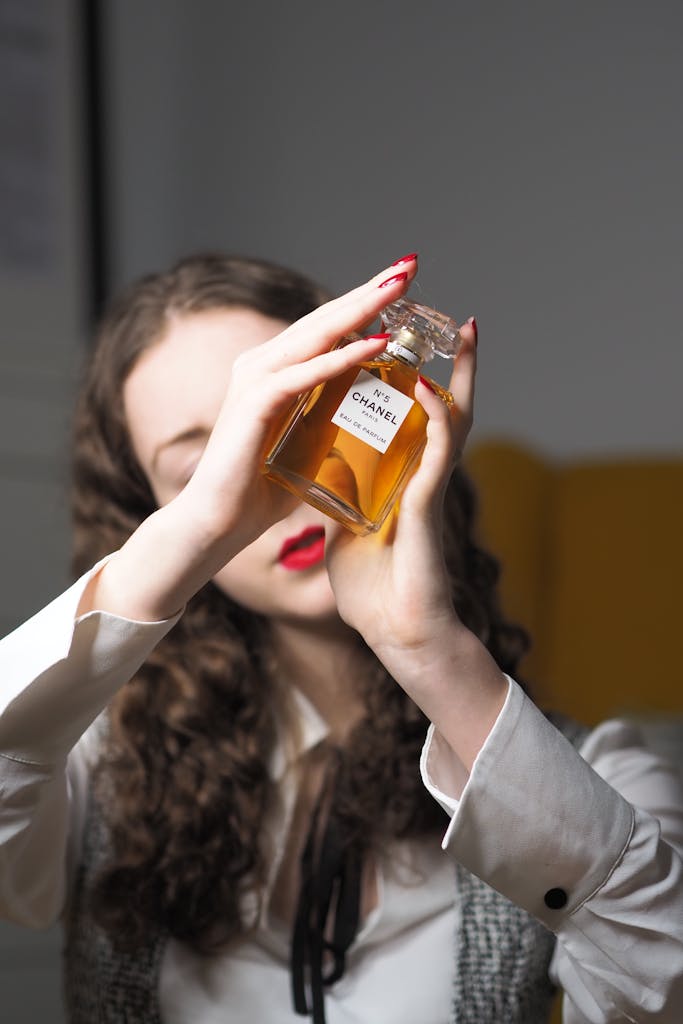 Stylish woman holding Chanel No. 5 bottle, highlighting elegance and luxury.